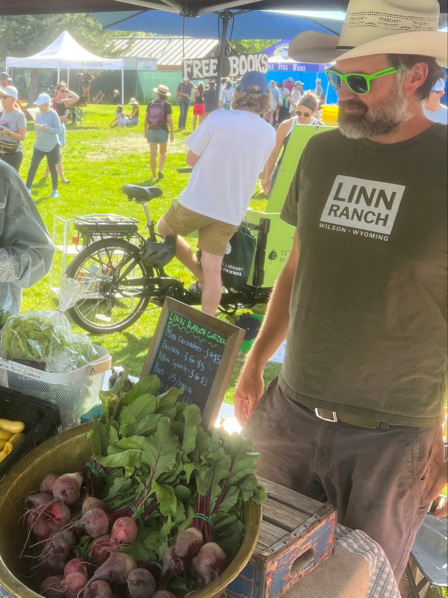 People at an outdoor market with a table displaying fresh produce.